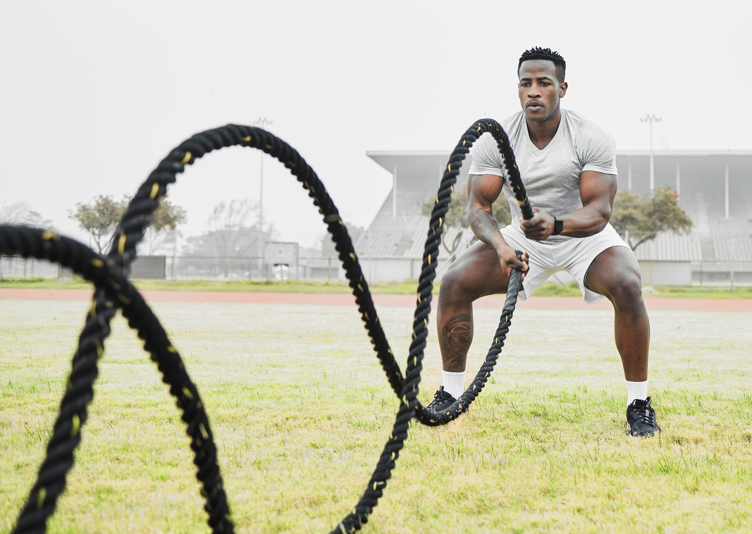Full length shot of a handsome young male athlete exercising with battle ropes outside.