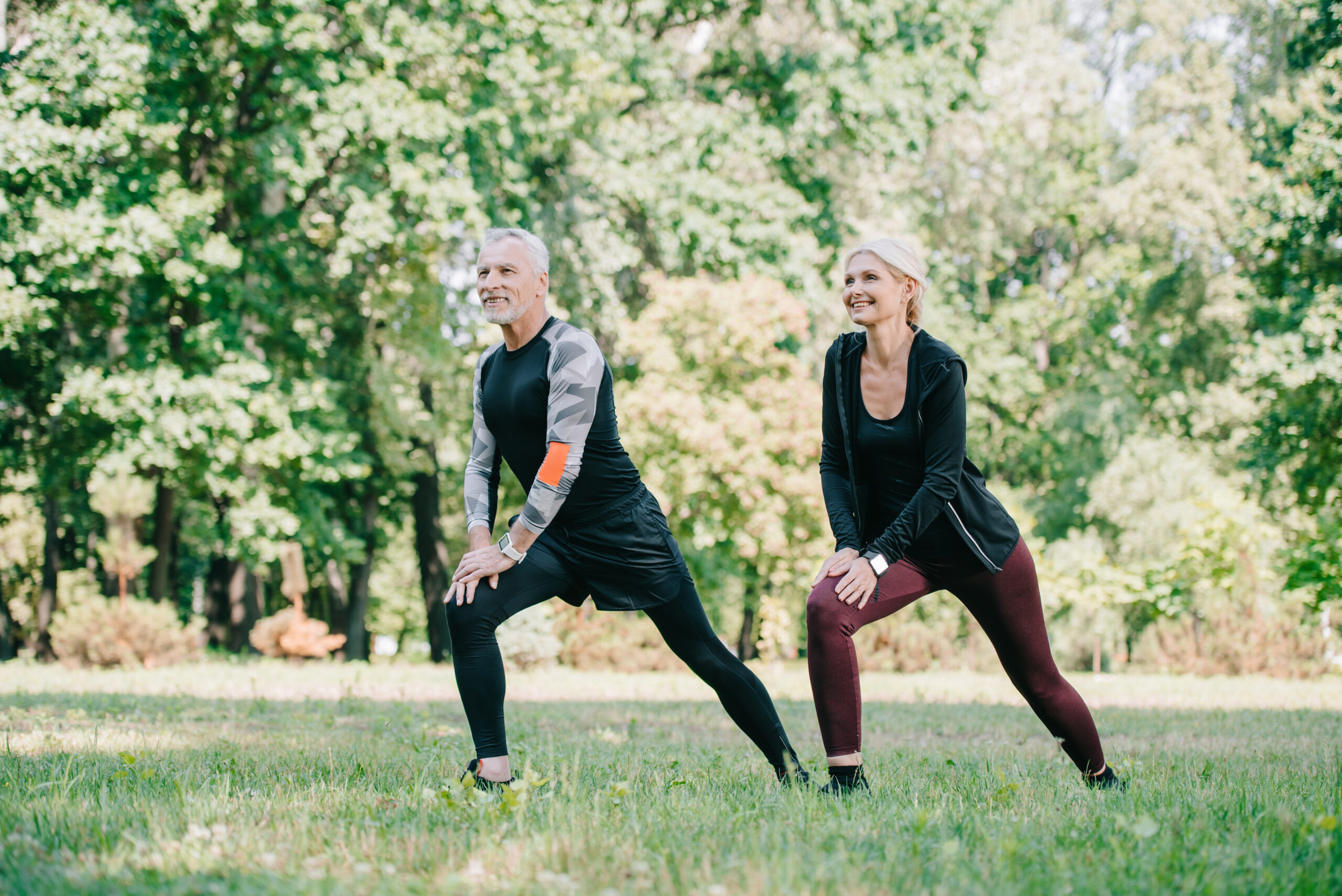 positive, mature sportsman and sportswoman doing lunges exercises and looking away